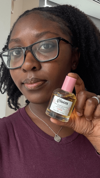 Allure associate beauty editor Annie BlayTettey holding a bottle of Gisou Honey Infused Hair Perfume